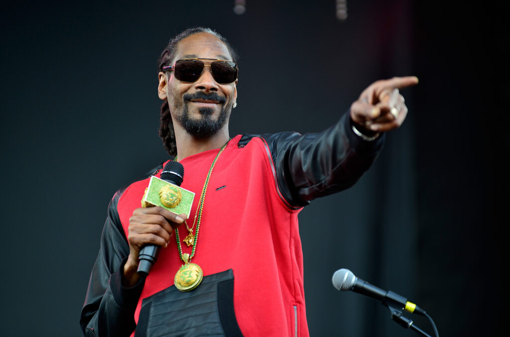 A black man with black and red hoodie pointing