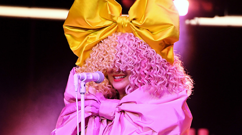 A woman wearing a pink wig with a pink bow dress smiling